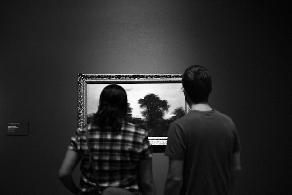 Two people viewing a painting in an art museum. Black and white detail enhancing mystery.